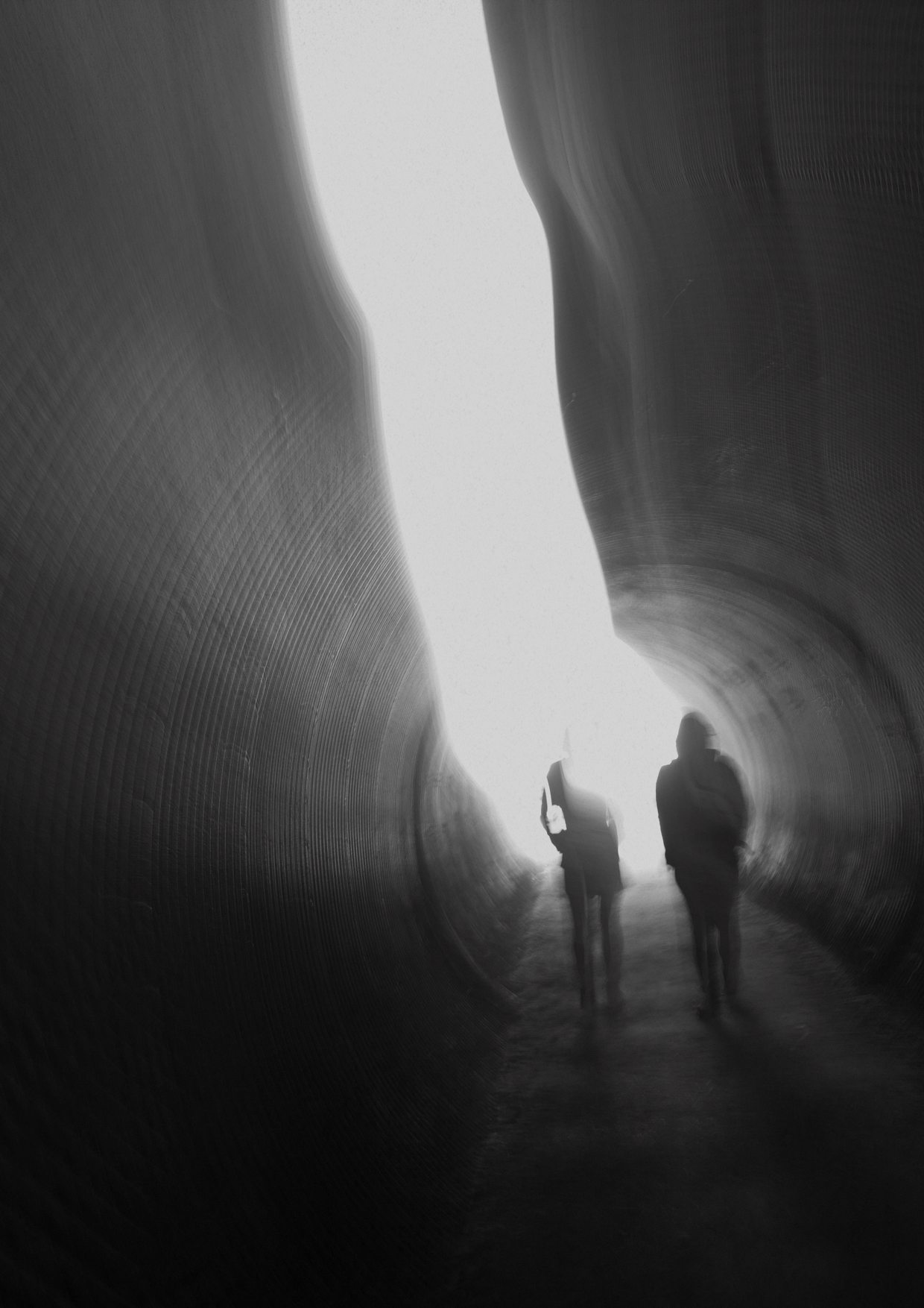 Twee silhouetten lopen samen door een tunnel naar het licht.